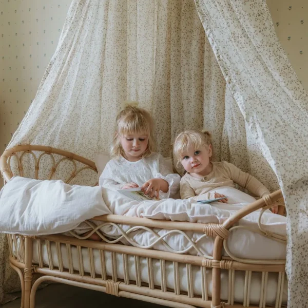 2 piger som sidder i en Cocoon Company junior seng med dyner og puder